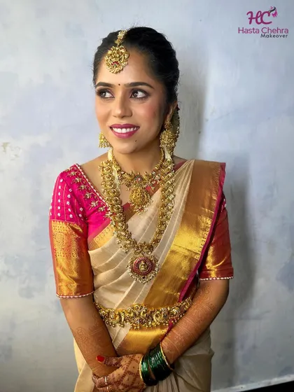 Our gorgeous bride Kavya on her muhurtham day. She chose a magnificent layered temple jewellery set with a statement choker and a long haram featuring a large, intricate pendant.