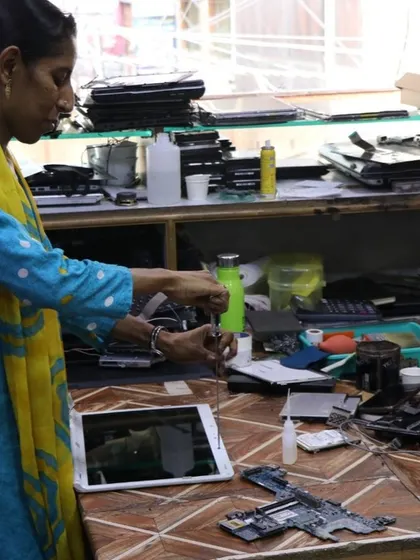 A technician works on repairing a tablet in a busy workshop. We connect people with skilled local repair professionals, promoting the repair economy and providing access to expert help.