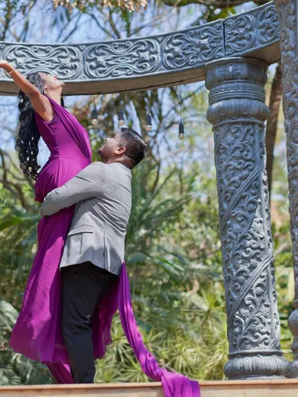 A dramatic and romantic pose from a pre-wedding shoot, with the bride's flowing purple gown creating a sense of movement and elegance.