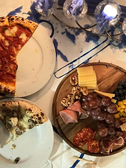 A perfect pairing for a cozy evening. This overhead shot shows slices of my Neapolitan pizza next to a carefully arranged charcuterie board with cheeses, cured meats, grapes, and walnuts.