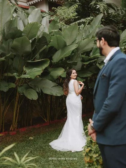 Akshatha looking back at Jeethesh during their first look. The lush green background makes this moment feel like it's straight out of a fairy tale.