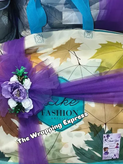 A large gift bag decorated with a purple net bow and flowers, part of a baby girl's welcome trousseau.