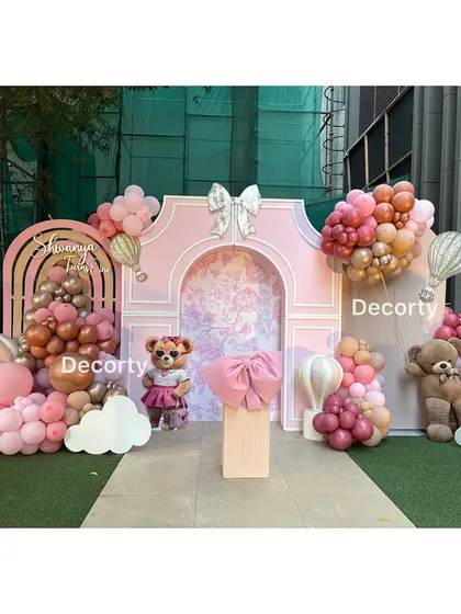 The main photo backdrop for a chic, pink Ralph Lauren-inspired birthday party, featuring teddy bears and a large bow.