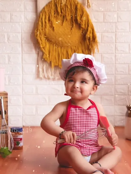 This little chef is having fun with a whisk, surrounded by ingredients in our playful kitchen setup.