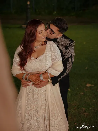A sweet, candid moment from an engagement party, with the groom stealing a kiss on the bride's cheek.