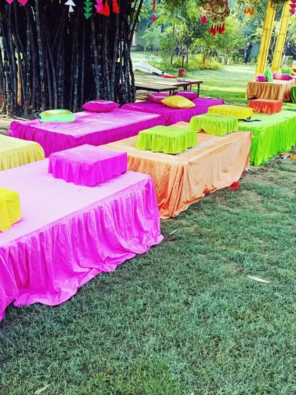 Colorful low-seating arrangements on a lush green lawn, perfect for a relaxed and vibrant Mehendi gathering.