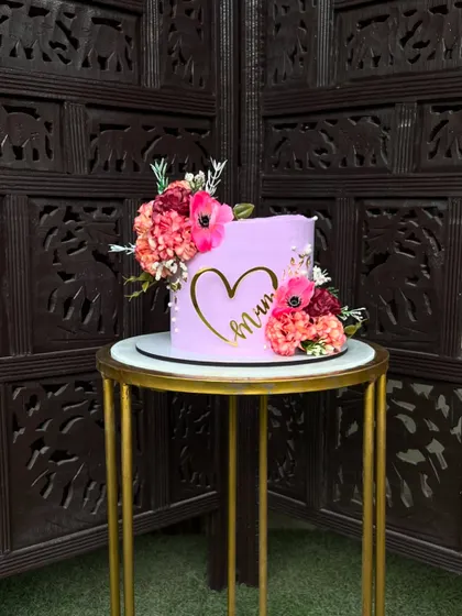 A minimalist purple cake for "Mum," featuring a simple gold heart outline and adorned with a few carefully placed fresh flowers.