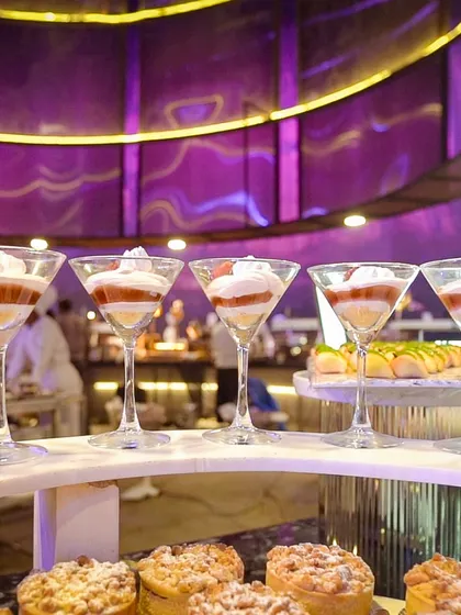 A row of our layered trifles, served in elegant martini glasses. The distinct layers of cake, cream, and fruit create a visually appealing dessert that is light and delicious.