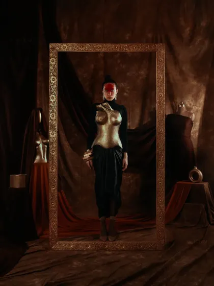 A powerful shot from the 'ASTRID' editorial, featuring a custom-made golden breastplate. The entire set, including the ornate frame, was designed to create a theatrical, museum-like quality, presenting fashion as wearable art.
