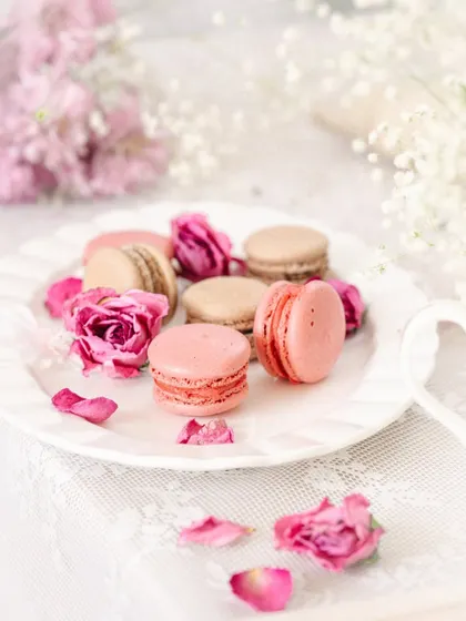 Macarons arranged on a plate with baby's breath flowers in the background, adding to the soft, romantic aesthetic.