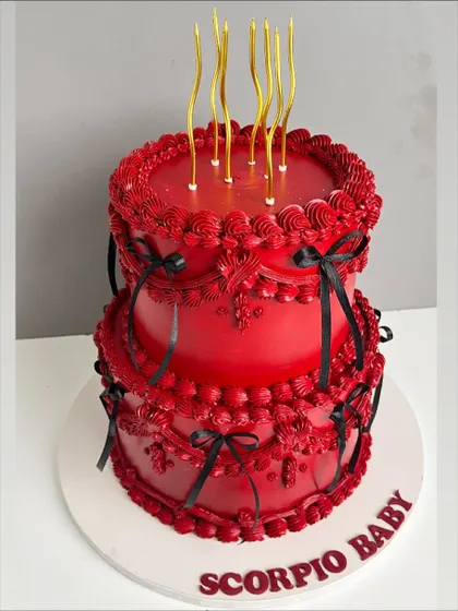 This cake was designed for a client who loves all things bold and dramatic. The deep red buttercream is adorned with intricate, hand-piped vintage details and delicate black ribbons, creating a striking two-tiered cake that is both fierce and elegant.