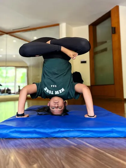Another student mastering the lotus headstand. We meet every student where they are and help them progress at their own pace.