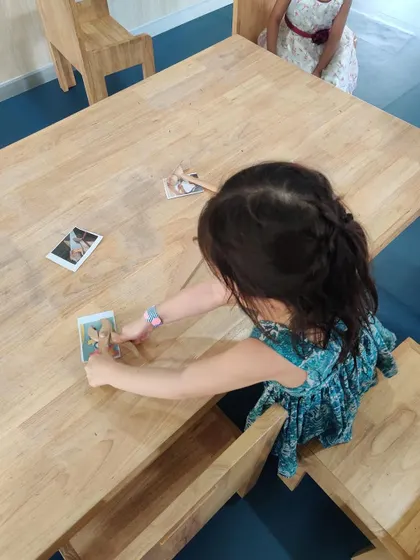 To recap our lesson on community helpers, a child works on a matching game, pairing wooden tools with pictures of them in use. This is a quiet, independent learning activity.