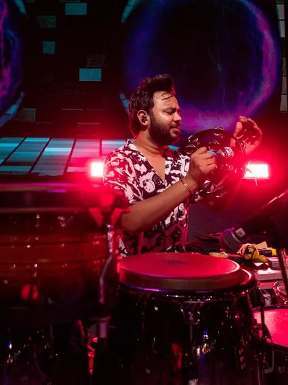 Playing the tambourine under the vibrant red stage lights. Even small instruments play a big role in building the overall energy of a song.