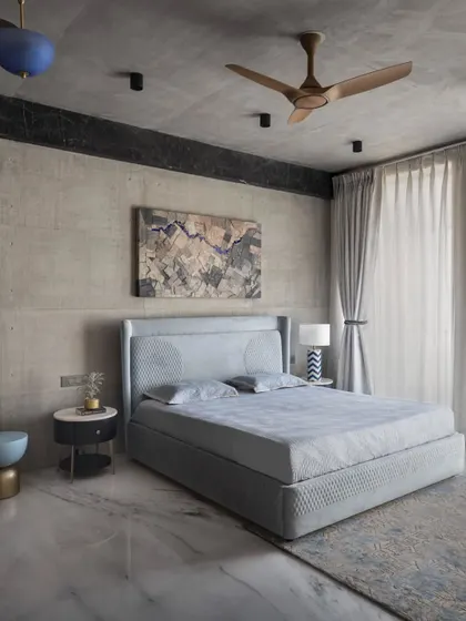 The concrete ceiling in this Swatantra Residence bedroom has circular cuts for pendant light fixtures, adding drama to the space. Natural light streams through the balcony, creating a place for relaxation and rejuvenation.