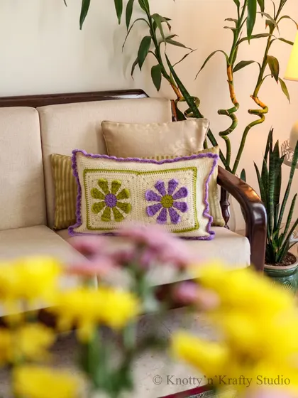 My floral cushion seen from afar, with fresh yellow flowers in the foreground. It shows how handmade decor can beautifully complement nature's own colours.