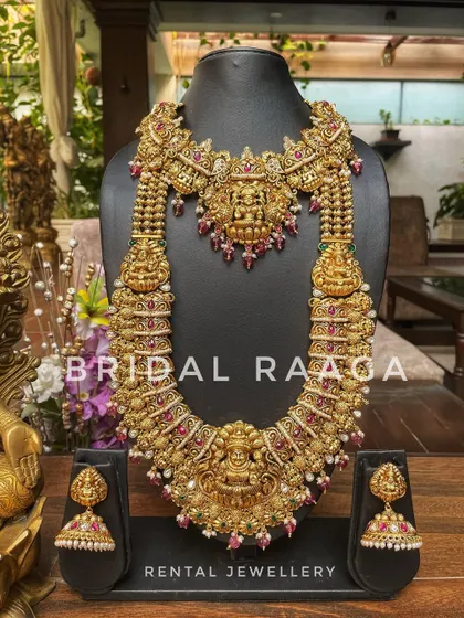 A heavy and ornate bridal set with a large Lakshmi choker and a matching long haram. This is perfect for a bride wanting a grand, traditional look.