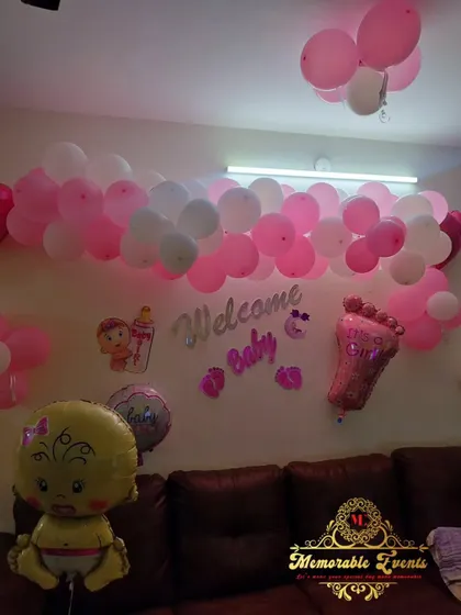 A 'Welcome Baby' decoration for a home, featuring pink and white balloons, foil balloons, and wall decals.