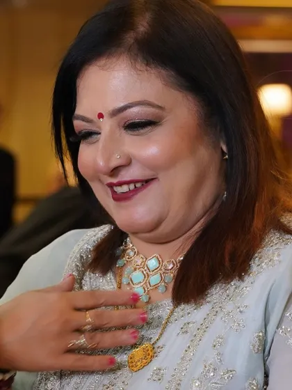 A candid, happy shot of a mother at a wedding function. Her makeup is fresh and radiant, with a lovely pop of color on her lips.