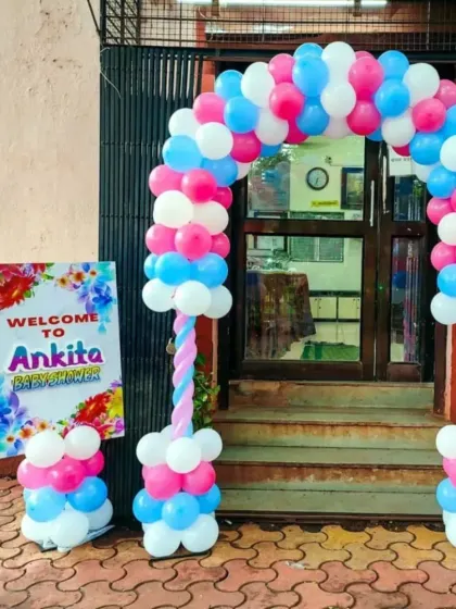 A colorful balloon arch pillar decoration for a baby shower entrance. The setup includes a personalized welcome sign for the mom-to-be, creating a warm welcome for guests.