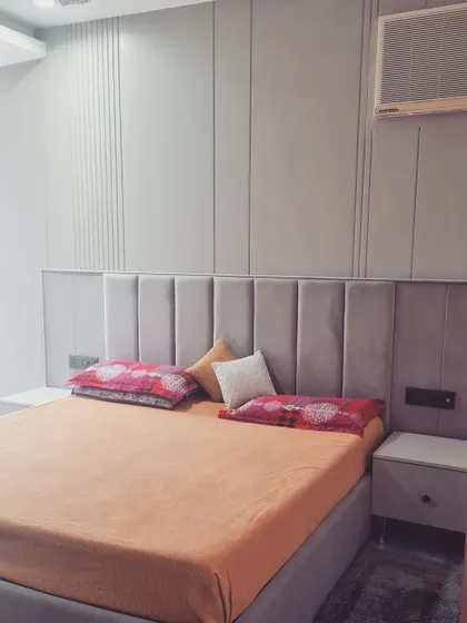 A completed bedroom featuring a simple, elegant wall with vertical grooves and a plush, tufted headboard.
