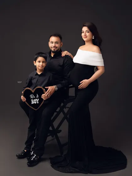 A classic family portrait. The older brother looks so proud, holding an "It's a Boy" sign. It's a beautiful way to announce the gender and include the whole family.
