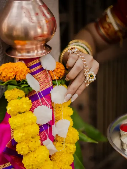 Details make the story. This close-up focuses on the hand-adorning the Gudi with a garland of sugar crystals and flowers, capturing the delicate and meaningful traditions of the festival.