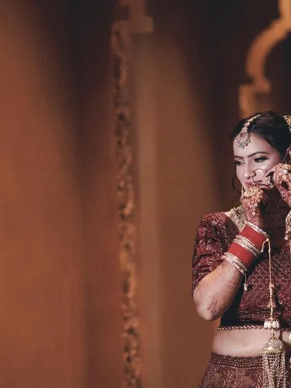 A candid shot of the bride adjusting her earring, captured in a beautifully lit corridor. This photo highlights the small, personal moments of the wedding day.