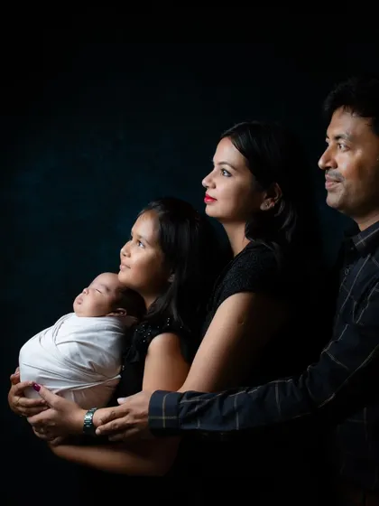 A beautiful color portrait of a family with their newborn and older daughter, all posed together looking towards the light.