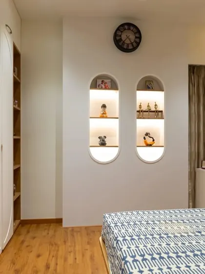 This bedroom features a wardrobe with an open shelving unit, perfect for displaying books or decorative items. The main wardrobe has handle-less doors with an arched design for a unique touch.