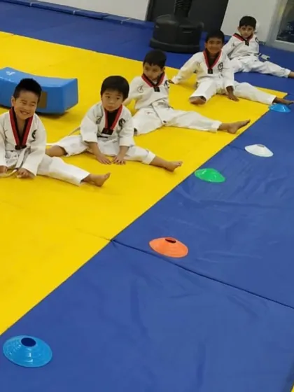 After a rigorous training session, flexibility is key. Our young students work on their splits and stretches, an essential part of Taekwondo that improves range of motion and prevents injury.