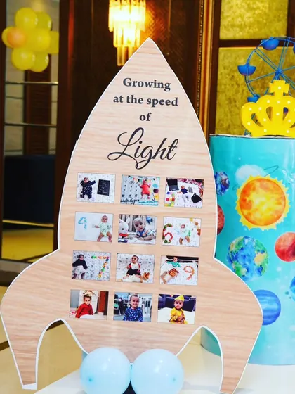 This custom rocket-shaped photo board was a unique detail for Yashbir's space-themed party. It displayed photos from his first year under the heading "Growing at the speed of Light," adding a sweet, personal touch.
