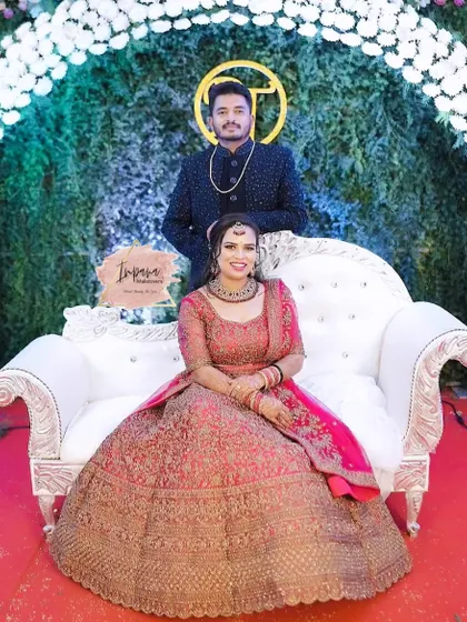 The happy couple posing for a photo at their reception. The bride's stunning pink lehenga is paired with a glamorous HD makeup look.