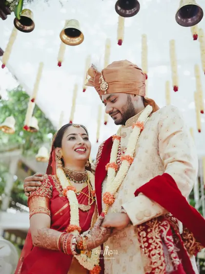 A beautiful candid moment of the couple, their smiles and traditional attire shining under the festive bells.