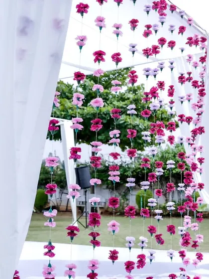 A beautiful curtain of hanging pink and white flowers creates a dreamy and romantic backdrop for a wedding ceremony.