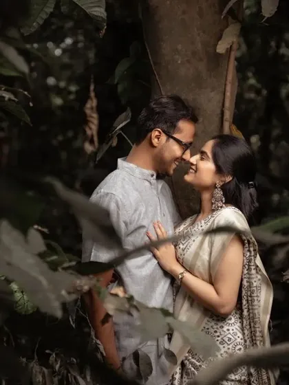 An intimate pre-wedding portrait in the woods, with the couple framed by leaves. The soft light and close embrace create a very romantic mood.