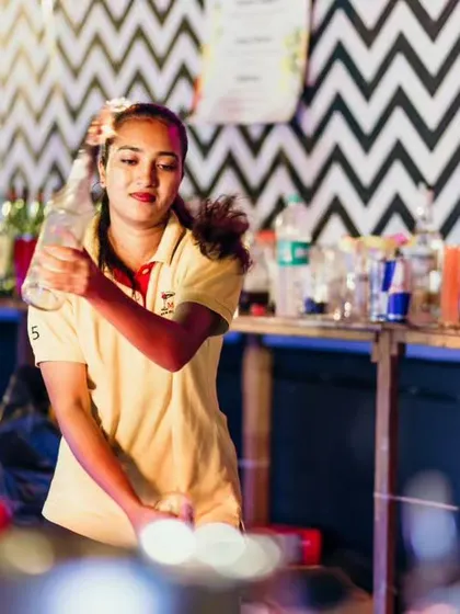 One of our female bartenders focused on a pour, showcasing the skill and diversity of our professional event team.