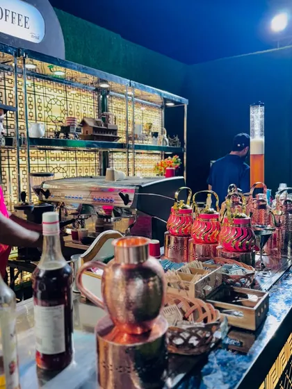 A barista at work behind the coffee bar, which is elegantly designed with gold lattice work.