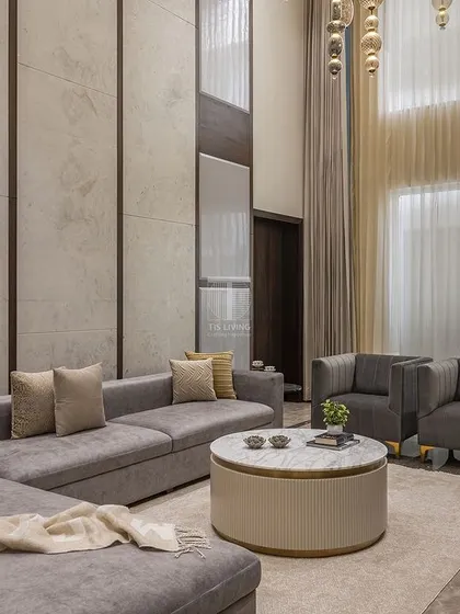 Another view of a double-height living room we designed. The large sectional sofa provides ample seating, while the round coffee table softens the geometry of the space. Every piece is scaled to feel right in this grand setting.
