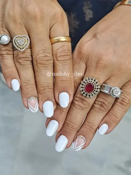 A classic white manicure with a stylish accent nail featuring geometric lines and glitter.