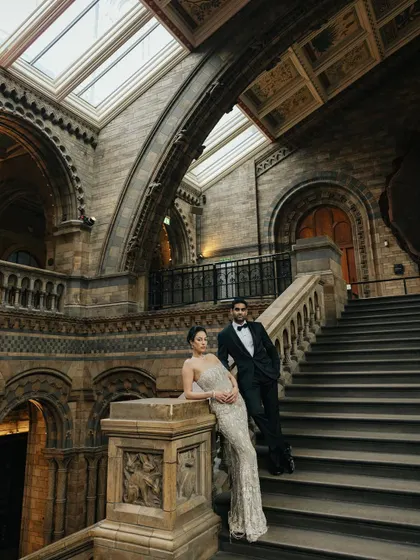 A grand portrait of Julia and Aditya on the iconic staircase of the Natural History Museum in London. This image showcases the epic scale and unique choice of their reception venue.
