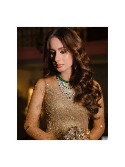 A close-up on the bride's stunning emerald necklace and her thoughtful expression. A portrait that is both beautiful and soulful.