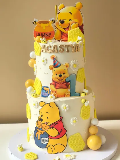 A full view of the two-tiered Winnie the Pooh cake, showcasing the sweet details and buzzing bees.