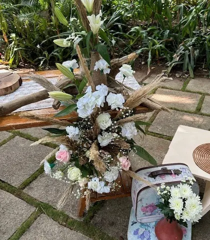 A close-up of a boho floral arrangement featuring white lilies, roses, and dried grasses. These natural, rustic bouquets are perfect for outdoor or bohemian-themed events.