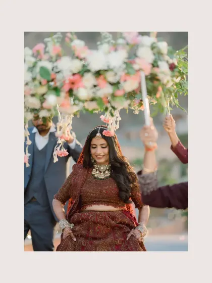 The bride's joyful entry under a floral canopy, her happiness evident in her dance-like steps.