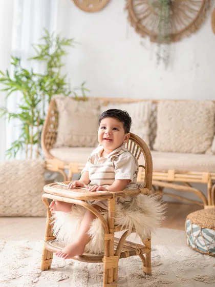 Sitting like a big boy in his high chair. This shot from a sitter session showcases the baby's confidence and adorable personality in a natural, boho-chic setting.