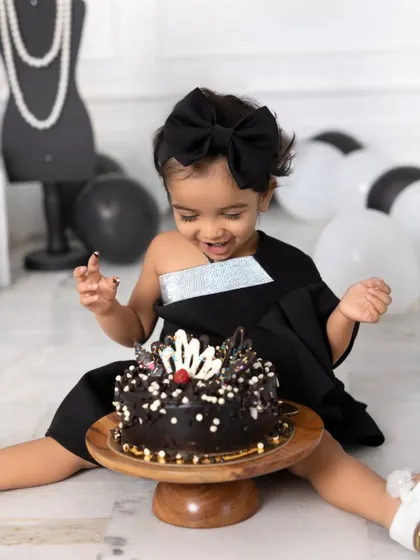 A cake smash with a side of high fashion. This little girl is all smiles as she gets ready to dig into her chic, Chanel-themed birthday cake.
