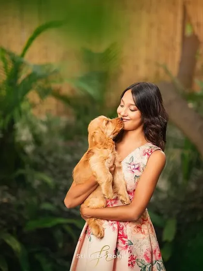 Unconditional love in a single frame. A girl shares a sweet kiss with a Cocker Spaniel puppy, surrounded by a lush, green backdrop. These are the moments that melt my heart.