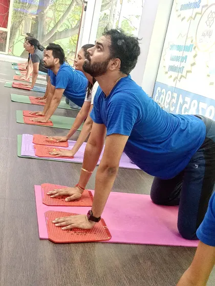 A group of students in Cat-Cow pose using acupressure plates under their hands for added sensory input.