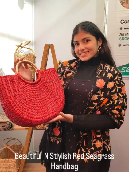 A customer proudly displays our bright red seagrass handbag. This image shows the bag's generous size and stylish shape, making it a perfect statement accessory.